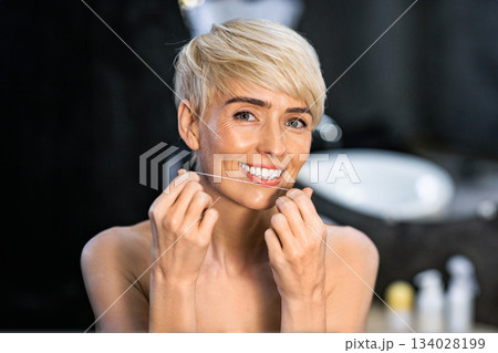 Oral Care. Lady Flossing Her White Teeth Doing Toothcare Routine Standing In Bathroom In The Morning. Copy Space Oral Care. Lady Flossing Her White Teeth Doing Toothcare Routine Standing In Bathroom In The Morning. Copy Space 134028199