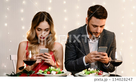 Social Media Addiction Concept. Couple spending time with their smartphones on romantic date in restaurant, ignoring each other 134028247