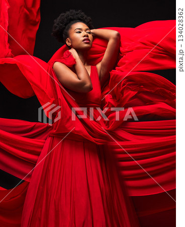 Beauty, black woman and art in fashion, fabric on dark background and motion in aesthetic movement. Flowing silk, fantasy and artistic, sensual African model in red creative designer dress in studio. Beauty, black woman and art in fashion, fabric on dark background and motion in aesthetic movement. Flowing silk, fantasy and artistic, sensual African model in red creative designer dress in studio. 134028362