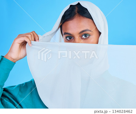 Muslim woman cover face with scarf in studio, blue background and color backdrop. Portrait, islamic female model and hijab for beauty, culture and confidence of religion, arabic fashion and style 134028462