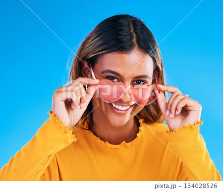 Fashion portrait, heart glasses and happy woman with young style, designer brand or casual summer outfit. Trendy gen z aesthetic, girl smile and female model face on blue background studio Fashion portrait, heart glasses and happy woman with young style, designer brand or casual summer outfit. Trendy gen z aesthetic, girl smile and female model face on blue background studio 134028526