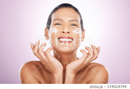 Face smile, cream and skincare of woman in studio isolated on a purple background. Mature, portrait and happy female model with dermatology lotion, creme and moisturizer cosmetics for healthy skin. Face smile, cream and skincare of woman in studio isolated on a purple background. Mature, portrait and happy female model with dermatology lotion, creme and moisturizer cosmetics for healthy skin. 134028794