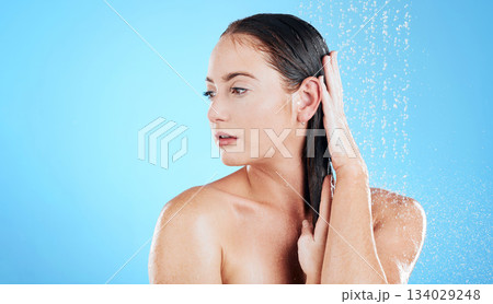 Shower, water and face of woman on blue background for grooming, cleaning and body wellness in studio. Skincare, bathroom mockup and serious girl model washing hair for hygiene, hydration and beauty Shower, water and face of woman on blue background for grooming, cleaning and body wellness in studio. Skincare, bathroom mockup and serious girl model washing hair for hygiene, hydration and beauty 134029248