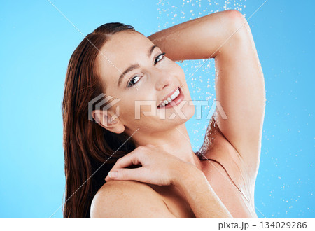 Water, shower and woman washing portrait in studio for skincare, wellness and clean body for self care. Happy female model face, splash or drops for cleaning, hygiene and cosmetics on blue background Water, shower and woman washing portrait in studio for skincare, wellness and clean body for self care. Happy female model face, splash or drops for cleaning, hygiene and cosmetics on blue background 134029286