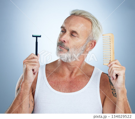 Senior man, shaver and comb thinking for grooming, skincare or hair removal against studio background. thoughtful mature male holding razor blade and brush for haircare, cosmetics or facial treatment Senior man, shaver and comb thinking for grooming, skincare or hair removal against studio background. thoughtful mature male holding razor blade and brush for haircare, cosmetics or facial treatment 134029522