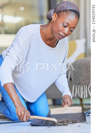 Maid, housekeeping and black woman cleaning and sweeping floor of a living room in a home or house for hygiene. Housekeeper, cleaner and domestic female remove dirt or dust with hand broom Maid, housekeeping and black woman cleaning and sweeping floor of a living room in a home or house for hygiene. Housekeeper, cleaner and domestic female remove dirt or dust with hand broom 134029745