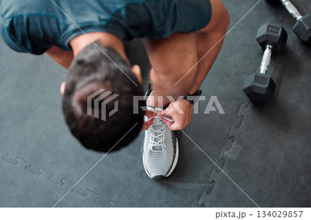 Top view, man and tie shoes in gym to start workout, training or exercise for sports. Athlete, male and tying laces on sneakers to prepare for running, cardio or exercising for health or fitness. Top view, man and tie shoes in gym to start workout, training or exercise for sports. Athlete, male and tying laces on sneakers to prepare for running, cardio or exercising for health or fitness. 134029857