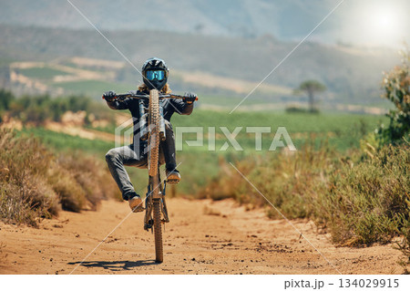 Cycling, fitness and person on a bicycle in the countryside for extreme sport, adrenaline and fun. Speed, action and cyclist on a dirt road for stunt, trick or training, freedom and balance in nature 134029915