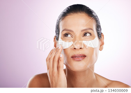 Face, skincare and woman eye patches in studio isolated on a purple background. Thinking, dermatology and serious female model with facial mask or cosmetics pads for healthy skin, collagen and beauty Face, skincare and woman eye patches in studio isolated on a purple background. Thinking, dermatology and serious female model with facial mask or cosmetics pads for healthy skin, collagen and beauty 134030009
