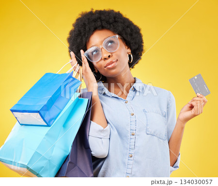 Shopping bag, retail thinking or black woman with credit card for sales product, fashion deal or mall store present. Commerce market, gift idea or customer contemplating isolated on yellow background Shopping bag, retail thinking or black woman with credit card for sales product, fashion deal or mall store present. Commerce market, gift idea or customer contemplating isolated on yellow background 134030057