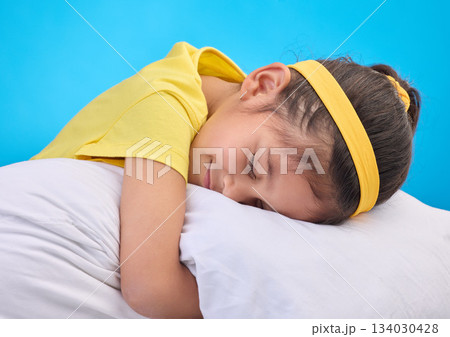 Calm young girl, pillow and sleep in a studio feeling tired, fatigue and ready for dreaming. Isolated, blue background and happy little child with pillows and closed eyes for sleeping, rest and nap Calm young girl, pillow and sleep in a studio feeling tired, fatigue and ready for dreaming. Isolated, blue background and happy little child with pillows and closed eyes for sleeping, rest and nap 134030428