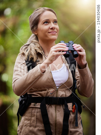 Binoculars, nature and happy woman hiking for travel journey, jungle adventure and forest explore with backpack gear. Sports hiker or person birdwatching and trekking in eco, green or tropical woods 134030486