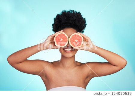 Black woman, face and smile with grapefruit for skincare nutrition, beauty or vitamin C against a blue studio background. Portrait of African female smiling with fruit for natural health and wellness Black woman, face and smile with grapefruit for skincare nutrition, beauty or vitamin C against a blue studio background. Portrait of African female smiling with fruit for natural health and wellness 134030639