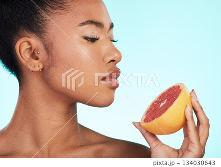 Grapefruit, woman and profile of a young model with skincare, fruit and wellness for diet. Isolated, blue background and studio with a person with beauty, cosmetics and healthy food for skin glow 134030643