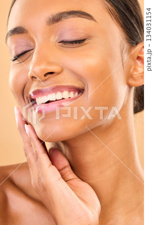 Beauty, face and smile of woman with makeup in studio for skincare, cosmetics and dermatology. Aesthetic female .hand for self care, natural skin and spa facial shine results on a brown background 134031154