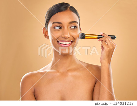 Indian woman, beauty and brush for makeup with smile, cosmetic tools, skin glow and face on studio background. Happy female, thinking and cosmetology, apply foundation or powder with self care 134031218