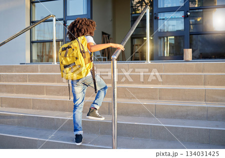 Education, back to school and student in the morning ready to start learning and studying at school. Child with backpack walking on academy steps going to class for study and academic lifestyle Education, back to school and student in the morning ready to start learning and studying at school. Child with backpack walking on academy steps going to class for study and academic lifestyle 134031425
