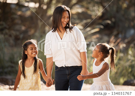 Family, children and holding hands with a mother and daughter siblings walking outdoor together in nature. Kids, love and happy with a woman, girl and sister taking a walk hand in hand while bonding 134031767