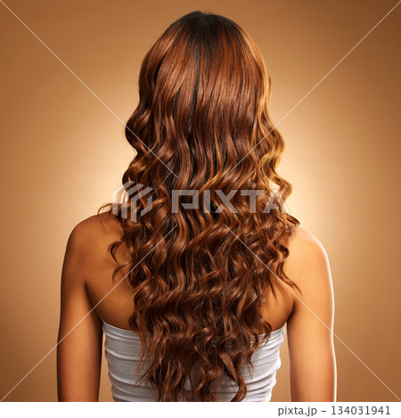 Back of hair, curls and woman for beauty, wellness and keratin treatment on brown background. Hairdresser mockup, salon studio and girl with curly hairstyle for growth, haircare texture or cosmetics 134031941