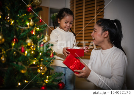 mother and toddler girl with gift box and Christmas tree in home at night mother and toddler girl with gift box and Christmas tree in home at night 134032176