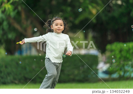 happy toddler girl running and playing soap bubble in park happy toddler girl running and playing soap bubble in park 134032249
