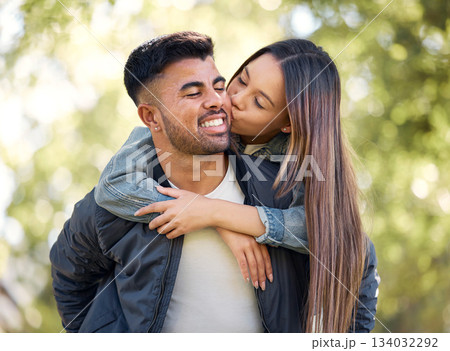 Couple, outdoor and piggyback with kiss for love, care and happiness together in summer. Young man and woman at nature park for affection, play or game on happy and romantic date or vacation to relax 134032292