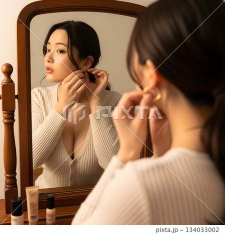 鏡を見ながらイヤリングをつける女性 134033002
