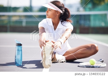 Tennis, warm up and leg stretching by black woman at court for sports, fitness and training on blurred background. Exercise, preparation and foot stretch by athletic girl player on floor before match Tennis, warm up and leg stretching by black woman at court for sports, fitness and training on blurred background. Exercise, preparation and foot stretch by athletic girl player on floor before match 134033122