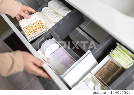 Top view of woman hands neatly organizing bathroom amenities and toiletries in drawer in bathroom. Top view of woman hands neatly organizing bathroom amenities and toiletries in drawer in bathroom. 134035503