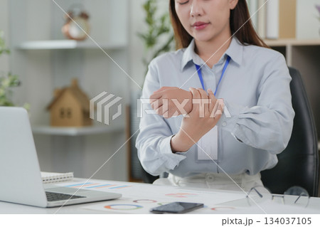 Office Syndrome: Professional woman holding wrist in pain at her workspace 134037105