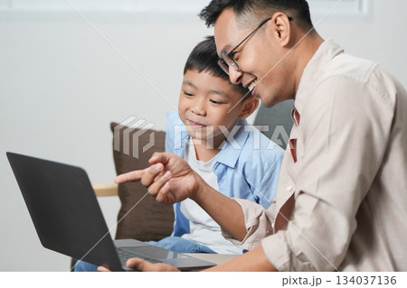 Father and son bonding over laptop, sharing learning moments Father and son bonding over laptop, sharing learning moments 134037136