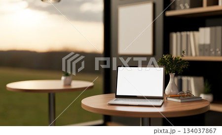 White screen laptop on wooden stool table next to bookshelf and glass wall of living room an office. 134037867
