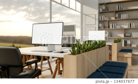 Blank screen computers on table with armchairs near partition bench in office with wide glass wall. 134037877