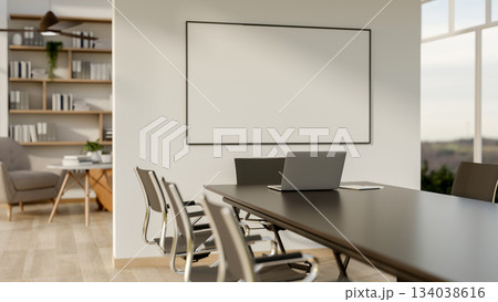 Black table with laptop and armchairs with blank board on wall between meeting room and living room. 134038616