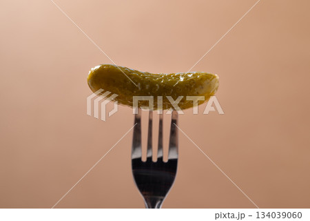 Pickled cucumber or Gherkin pickle with fork on brown background Pickled cucumber or Gherkin pickle with fork on brown background 134039060