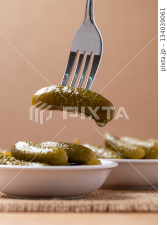 Pickled cucumber or Gherkin pickle in a bowl with fork on brown background Pickled cucumber or Gherkin pickle in a bowl with fork on brown background 134039061