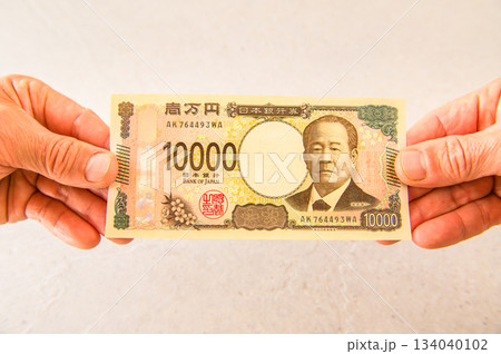 100ドル札1枚と1万円札1枚を持つアングルショット 134040102