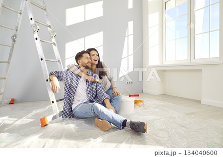 Happy young couple planning home repair while sitting on floor in living room 134040600