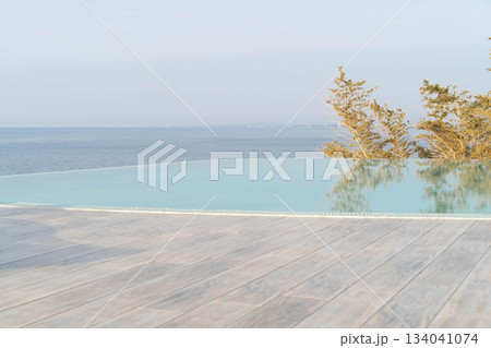 A stunning infinity pool stretches out towards the sea, creating a breathtaking view of tranquil waters. Front view, focus on the foreground. 134041074