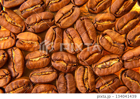 Close-up of roasted coffee beans on a lustrous golden tray Close-up of roasted coffee beans on a lustrous golden tray 134041439