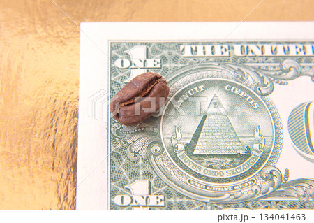 coffee bean, partially open, rests on a U.S. one-dollar bill, juxtaposing organic coffee bean, partially open, rests on a U.S. one-dollar bill, juxtaposing organic 134041463
