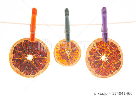 dried pieces of different citrus fruits hang on colored clothespins 134041466