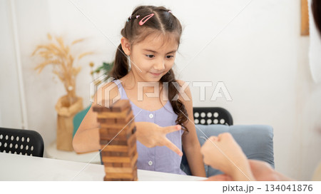 Asian kid or a little girl playing a rock paper scissors with parent while building a a wooden tower 134041876