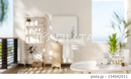 Marble stool table with towels and spa essentials in a bathroom with white wall and sea view outside 134042011