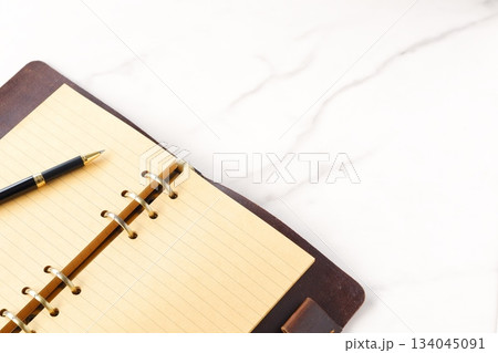 リング式のシステム手帳を開いてデスクワークをしているイメージ 134045091