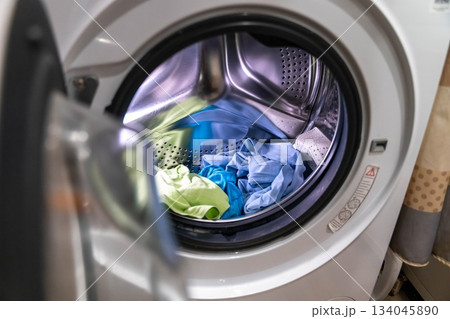 Washing clothes in a laundry machine at home in the morning hours of the day Washing clothes in a laundry machine at home in the morning hours of the day 134045890