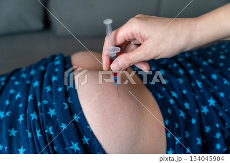 child receiving a medical injection at home during evening hours child receiving a medical injection at home during evening hours 134045904