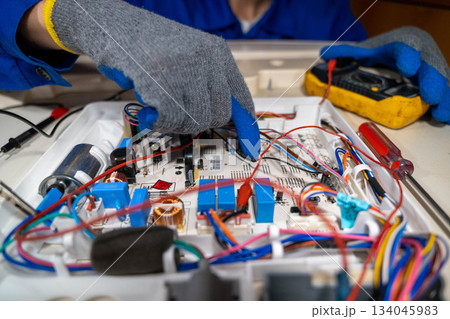 Technician repairs electronic circuit board in workshop during daylight hours 134045983