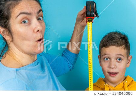 mather measures height of child with measuring tape in blue room mather measures height of child with measuring tape in blue room 134046090