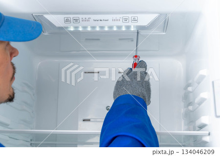 Repair worker fixes inside of refrigerator at home during day Repair worker fixes inside of refrigerator at home during day 134046209
